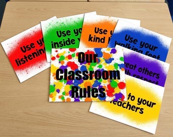 Può includere: Un set di cartelli rettangolari per l'aula con bordi in stile vernice spray. Il cartello centrale riporta la scritta Our Classroom Rules su uno sfondo con schizzi di vernice multicolore. Altri cartelli includono testi come Use your listening ears, Use inside voices, Use kind hands, Use your walking feet, Treat others with respect e Listen to your teachers.