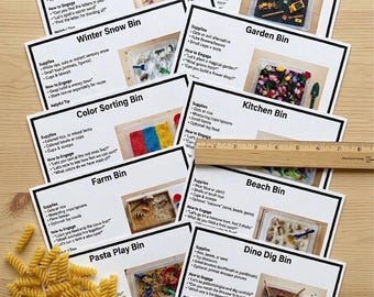 Può includere: Un insieme di schede di attività educative per bambini, con vari temi come un contenitore per la ricerca di lettere e un contenitore per la costruzione. Le schede sono disposte su una superficie di legno, con pasta e un righello.