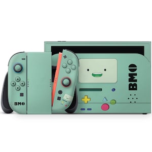 Pode incluir: Uma consola Nintendo Switch e comandos Joy-Con verde-menta com um design BMO de Adventure Time. A consola tem um ecrã e um gráfico da cara do BMO. Os Joy-Cons são verde-menta com detalhes laranja e o texto "BMO".