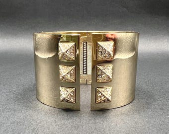 Pulseira larga articulada com strass dourados e detalhes escandalosos da Victoria's Secret.