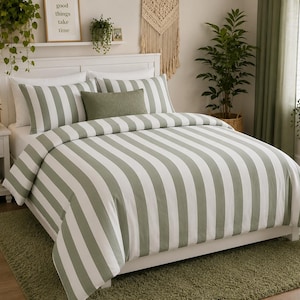 May include: A bed featuring a white and sage green vertical striped duvet cover and matching pillowcases. A solid sage green rectangular accent pillow is centered on the bed. The bedding is set on a white wooden frame with a white headboard.