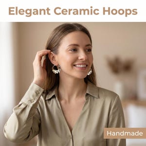 Puede incluir: Elegantes pendientes de aro de cerámica con detalles blancos y dorados. Los pendientes son hechos a mano y presentan un diseño delicado. La imagen también incluye el texto "Elegant Ceramic Hoops" y "Handmade".