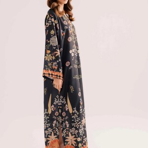 May include: A long, black dress with a floral pattern in shades of orange, yellow, and green. The dress has long sleeves and a slit up the side. The hemline and sleeve cuffs have a patterned border.