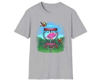 May include: A gray t-shirt featuring a colorful graphic of a disc golf basket with a pink disc. The design includes the text "LET'S GROW" and "DISC GOLF LOVE", along with illustrations of hummingbirds and roses.