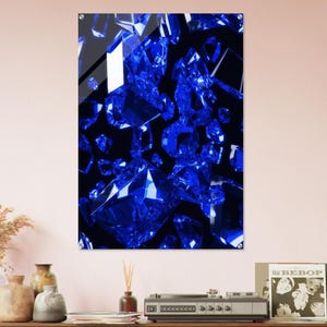 Puede incluir: Una impresión artística enmarcada que presenta un grupo de cristales azules vibrantes sobre un fondo negro. Los cristales están representados con facetas afiladas y reflectantes, creando un efecto visual dinámico y llamativo. La obra de arte está montada en una pared.