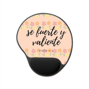 Puede incluir: Una alfombrilla de ratón con reposamuñecas negro y estampado floral. La alfombrilla presenta el texto "se fuerte y valiente" y "Josue 1:9" en escritura negra sobre un fondo melocotón, con un borde de flores.