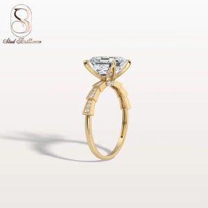 K&ouml;nnte beinhalten: Ein Goldring mit einem gro&szlig;en, im Smaragdschliff facettierten Mittelstein, der von vier Krappen gehalten wird. Die Ringschiene zeigt ein gestuftes, geometrisches Motiv mit kleinen Pav&eacute;-Diamanten an den Schultern und einer glatten Schiene.