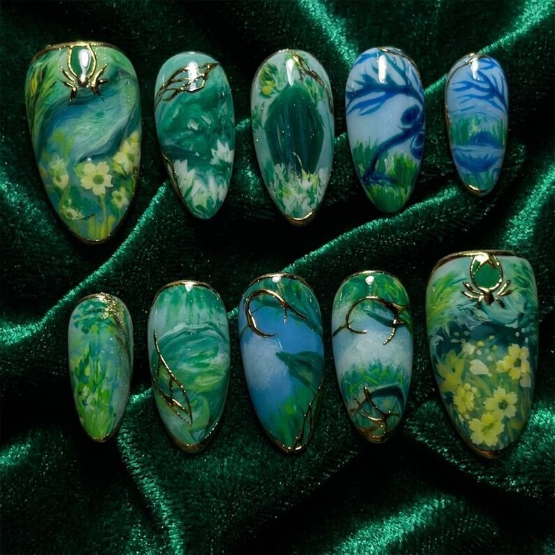 May include: A collection of ten artificial nails, each with a unique nature-themed design. The nails display green and blue landscapes with gold detailing. Some feature floral elements, while others have abstract patterns.