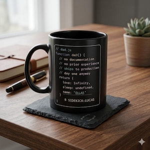 May include: Black coffee mug with a programming code design. The mug features text including "dad.js", "ELLAS", and "LUCAS". The mug is on a black square coaster, with a pen and notebook in the background.