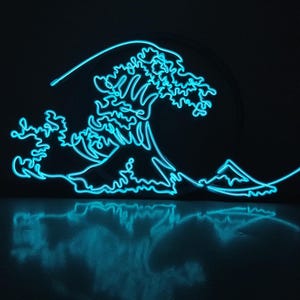 Puede incluir: Un diseño de ola azul neón sobre un fondo negro. La obra de arte representa una ola oceánica estilizada con una montaña a lo lejos. La luz de neón se refleja en la superficie de abajo, creando un efecto de espejo.