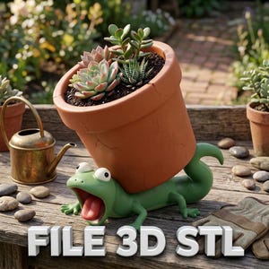 May include: A terracotta-colored flower pot filled with succulents, supported by a green lizard figurine. The lizard has an open mouth and a long red tongue. A small brass watering can is to the left. The text "FILE 3D STL" is at the bottom.