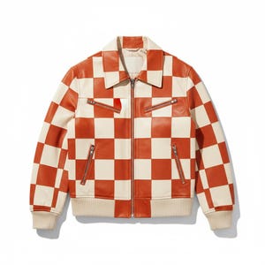 Könnte beinhalten: Lederjacke mit cremefarbenem und orangefarbenem Schachbrettmuster. Die Jacke hat einen Reißverschluss, zwei Brusttaschen und zwei Seitentaschen. Die Manschetten und der Saum sind cremefarben.