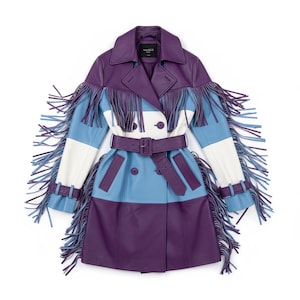 Könnte beinhalten: Ein farbblockierter Ledertrenchcoat in Lila, Weiß und Blau. Der Mantel hat lange Fransen an den Ärmeln und Schultern, einen Taillengürtel und einen doppelreihigen Verschluss. Der Mantel hat einen klassischen Kragen.