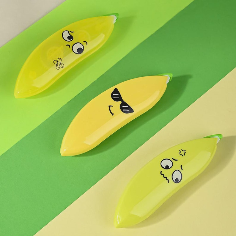 May include: Three banana-shaped tape dispensers with cartoon faces. One is yellow with sunglasses, another is yellow with a bandage, and the third is light green with an angry face. The background is a diagonal pattern of green and yellow.
