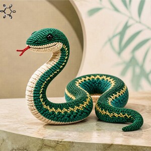 Puede incluir: Una serpiente de ganchillo amigurumi con escamas verde oscuro, vientre color crema y lengua roja bífida. El cuerpo presenta detalles bordados en amarillo a los lados. El texto dice Amigurumi Crochet Snake y fresh and colourful pattern.