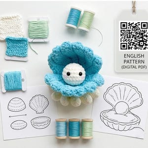 May include: A crocheted blue seashell with a white pearl, surrounded by spools of blue and green yarn. Includes a digital PDF pattern with a QR code and the text "ENGLISH PATTERN (DIGITAL PDF)". Also shown are crochet samples and shell diagrams.