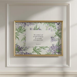 Puede incluir: Una impresión de arte mural rectangular en un marco dorado con un panel central blanco y el texto en negro: She is clothed with strength and dignity; she can laugh at the days to come. Proverbs 31:25. El borde muestra flores de glicinia.
