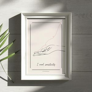 May include: White framed art print featuring a minimalist line drawing of a hand with a pink line extending from it. The text "I need sensitivity" is below the drawing. The artwork is on a light beige background.