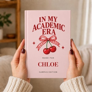 May include: A light pink hardcover book featuring the red text IN MY ACADEMIC ERA, a red and white gingham bow tied around two red cherries, and the text MADE FOR CHLOE CAMPUS EDITION printed in red on the front cover.