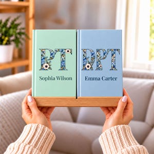 May include: Two hardcover books displayed on a wooden stand. The left book is mint green with the letters PT and the name Sophia Wilson. The right book is light blue with the letters DPT and the name Emma Carter. Both feature floral patterns.