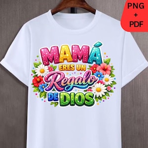 May include: White t-shirt with a colorful floral design and the text "MAMA ERES UN Regalo DE DIOS" in a vibrant, glittery font. The design includes pink, blue, and green letters, surrounded by flowers. The shirt has short sleeves and a crew neck.