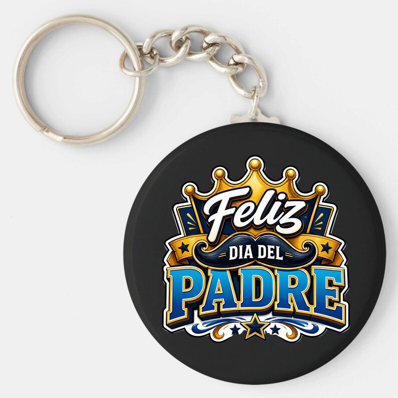 May include: A black keychain with a silver ring and chain. The round pendant features the words "Feliz Dia Del Padre" in blue and gold, with a crown and mustache design.