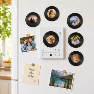May include: A set of black circular vinyl record photo frames and a white rectangular music player magnet. The player features a central record graphic, playback icons, and a heart symbol. Two rectangular photos and a note reading Good Vibes Only.