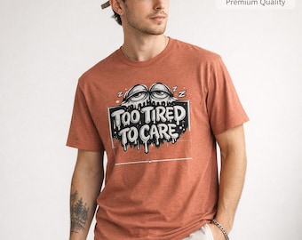 Camiseta con estampado gráfico "Too Tired To Care" (Demasiado cansado para preocuparse), diseño tipográfico de ojos soñolientos.