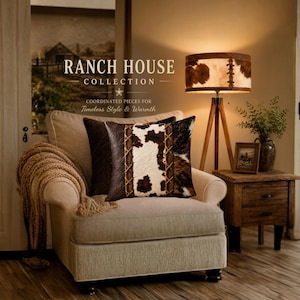 A square throw pillow featuring a central panel of white and brown cowhide print flanked by dark brown cowhide textured panels, accented with vertical brown leather print.