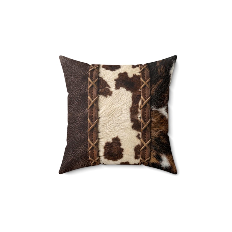May include: A square throw pillow featuring a central panel of white and brown cowhide print flanked by two vertical strips of brown faux leather with a crisscross stitched pattern, bordered by solid dark brown textured faux leather sides.
