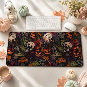 May include: A rectangular desk mat featuring a dark Halloween-themed print with skulls, jack-o'-lanterns, ghosts, haunted houses, spiderwebs, and a full moon. The design includes the text "TRICK OR TREAT" and "HAPPY HALLOWEEN" in orange lettering.
