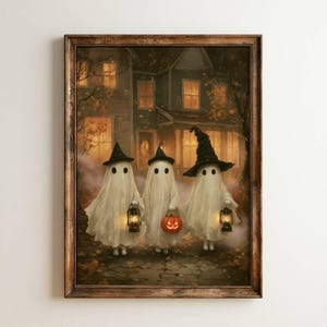 May include: A framed wall art print depicting three white ghost figures wearing black pointed hats standing in front of a house at night. Two ghosts carry glowing lanterns, while the center ghost holds an orange jack-o'-lantern pumpkin bucket.