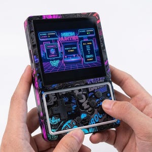 May include: A portable handheld gaming console featuring a black casing with a vibrant neon pink and blue graphic pattern. The screen displays a game titled Neon Hunter with retro arcade graphics. The device includes a black D-pad and four buttons.