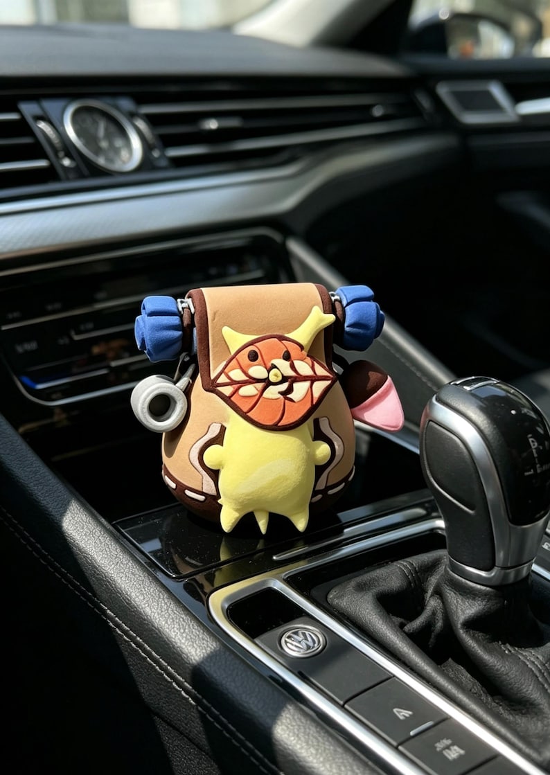 May include: A brown and yellow cartoon character car accessory. The accessory has a backpack design with blue straps and a smiling face. The accessory is sitting on a car's dashboard.