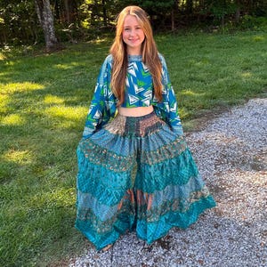Peut inclure: Ensemble deux pièces avec un haut court bleu et turquoise à motifs géométriques et manches longues. Le pantalon large assorti est à plusieurs niveaux avec un motif patchwork dans les tons turquoise, marron et orange. Idéal pour une tenue décontractée.