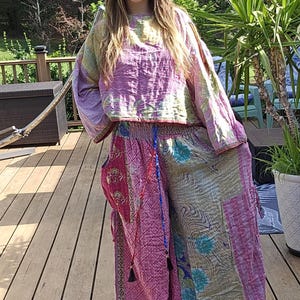 May include: A two-piece outfit featuring a tie-dye top in shades of pink, yellow, and green, paired with patchwork pants in pink and beige. The pants have a wide leg design and a drawstring waist. The outfit is casual and bohemian in style.