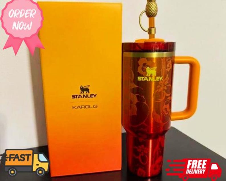 May include: A red and orange Stanley Karol G travel mug with a handle and a pineapple-shaped top. The mug is next to a matching box with the Stanley logo and Karol G's name. The words "Order Now" are in a pink circle.