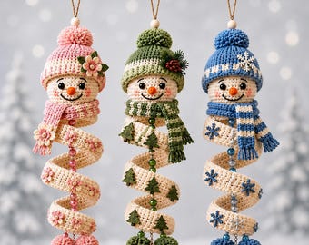 May include: Three hanging crochet snowman ornaments with spiral bodies. The left snowman wears a pink hat and scarf with flowers. The middle snowman has a green hat and scarf with pine trees. The right snowman features a blue hat and scarf with snowflakes.
