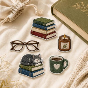 May include: A set of five embroidered patches featuring a stack of four books, a pair of brown round glasses, a lit candle in a jar, a gray cat sleeping on two books, and a green mug with a white heart design, all arranged on a cream fabric surface.