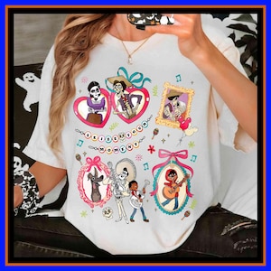 May include: White t-shirt with colourful illustrations from the film Coco. The design includes framed character images, musical notes, and the phrase "Seize Your Moment". The shirt has a crew neck and short sleeves.