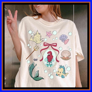 Unisex graphic tee featuring a mermaid princess, seashell, ocean castle, and underwater fantasy design, perfect for kids, adults, matching family outfits, vacations, and fairytale gifts.