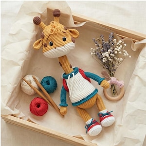 May include: A handcrafted crochet giraffe toy, featuring a yellow body, brown spots, and a white and blue outfit. The giraffe wears red and white trainers. The image also shows yarn, knitting needles, and a small flower bouquet.