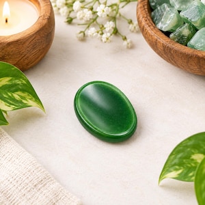 Può includere: Una pietra da preoccupazione ovale e liscia di colore verde con un centro concavo. La superficie lucida della gemma verde scuro riflette la luce, mettendo in risalto il suo colore solido e uniforme e i bordi arrotondati dal design semplice.