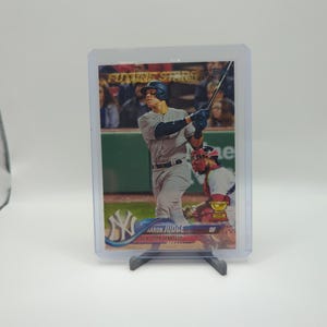 May include: A baseball card featuring Aaron Judge of the New York Yankees in a batting stance. The card is labeled "Future Stars" and is encased in a protective sleeve. The Yankees logo is visible.
