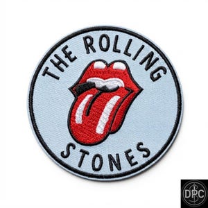 Peut inclure: Un écusson brodé circulaire avec un fond bleu clair et une bordure noire. Au centre se trouve le logo emblématique des lèvres et de la langue rouges avec des accents blancs. Le texte THE ROLLING STONES est brodé en noir sur le bord.