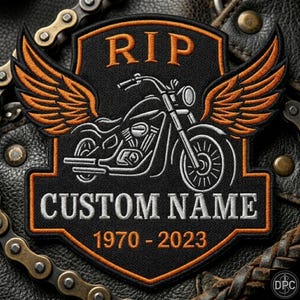 May include: A black shield-shaped embroidered patch featuring orange wings, a white motorcycle outline, and the text RIP, CUSTOM NAME, and 1970-2023. The patch has an orange border and is displayed against a dark textured leather background.