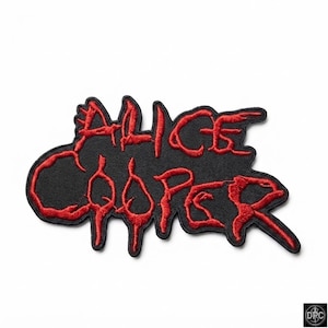 May include: A black embroidered patch featuring the text Alice Cooper in a stylized red font. The lettering has a dripping, jagged appearance with a thick black border surrounding the red embroidery, creating a distinct contrast against the black base.