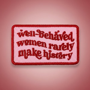 以下が含まれることがあります： ピンク色の背景と赤い縁取りの長方形の刺繍パッチ。「well-behaved women rarely make history」というフレーズが赤い様式化された文字で表示されています。