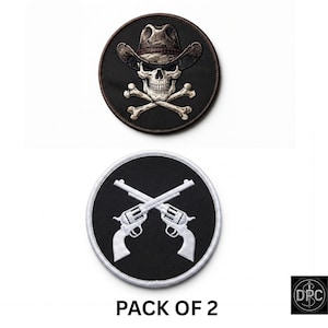 May include: A pack of two circular embroidered patches. The top patch features a skull wearing a cowboy hat above crossed bones on a black background. The bottom patch displays two crossed white revolvers on a black background with white border.