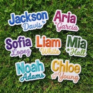 May include: Seven embroidered name patches featuring various first and last names in different colors and fonts. Each patch displays a first name in a bold, block-style font above a cursive last name, accented with small icons like stars, hearts, or rockets.